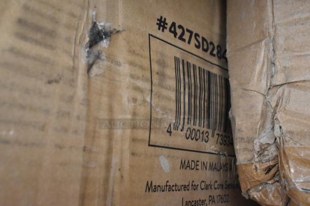 Damaged cardboard box with barcode #427SD286, highlighting scratches and dents. Label reads "Made in Malaysia for Clark Core Services, Lancaster, PA 17602."