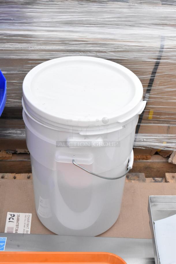 White plastic bucket with sealed lid, on pallet with other stacked items. Includes orange trays and labeled chair mat. New condition.