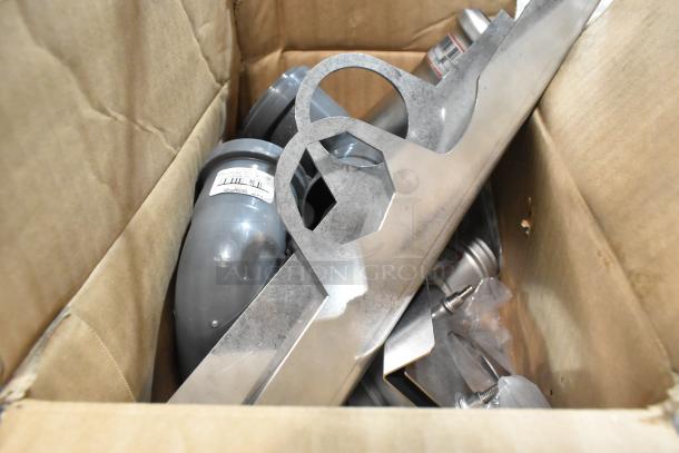 Two-tier lot of various items in a box, featuring metal pieces and containers with visible barcodes, assorted condition.