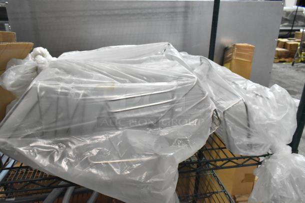Two-tier lot of various items on a metal rack, covered in clear plastic, including metal baskets. Suitable for storage.