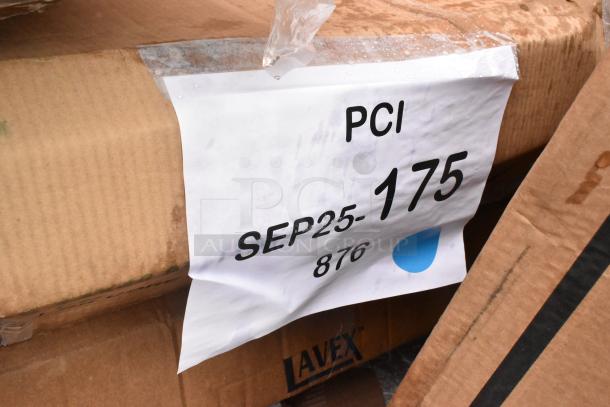 Cardboard box with label showing "PCI SEP25-175 876" on dampened surface. Marks indicate auction lot. Contains new scratch and dent items like a wok, dunnage rack, and dispenser.