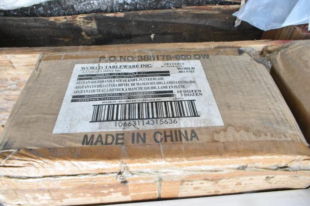 Cardboard box labeled "World Tableware Inc" containing Aegean solid handle steak knives with fluted blades. Made in China. Scratch and dent condition; 18 dozen knives per pack.