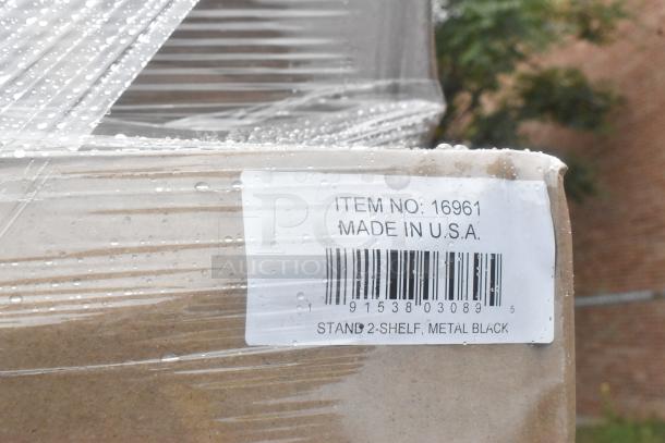 Wrapped pallet of scratch and dent boxes labeled "Item No: 16961," "Made in U.S.A.," "Stand 2-Shelf, Metal Black."