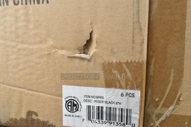 Cardboard box with damage, labeled "American Metalcraft." Contains 6 black 6"H risers, scratch and dent condition.