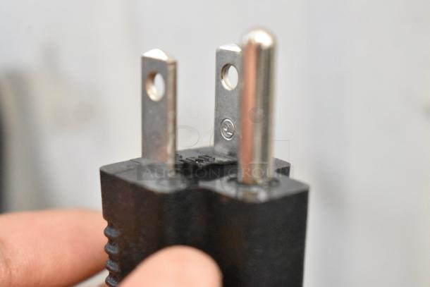 Close-up view of a two-prong electrical plug showing metal prongs and black plastic housing in detail.