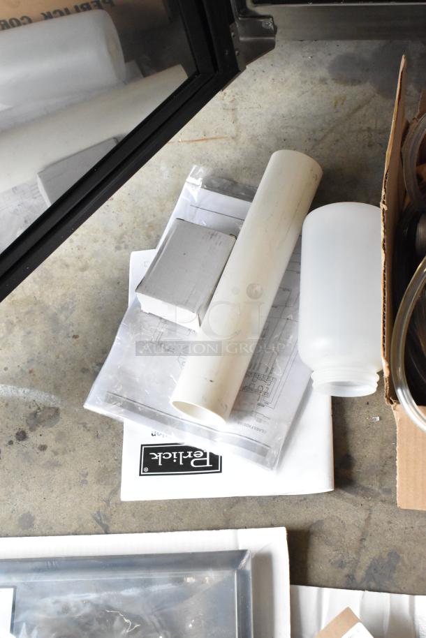 Perlick DDS36 kegerator parts and manual on concrete floor, including PVC pipe, plastic bottle, and labeled box.