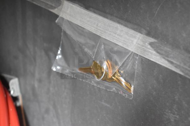 Plastic bag with keys for Perlick DDS36 kegerator, attached to a surface with tape.