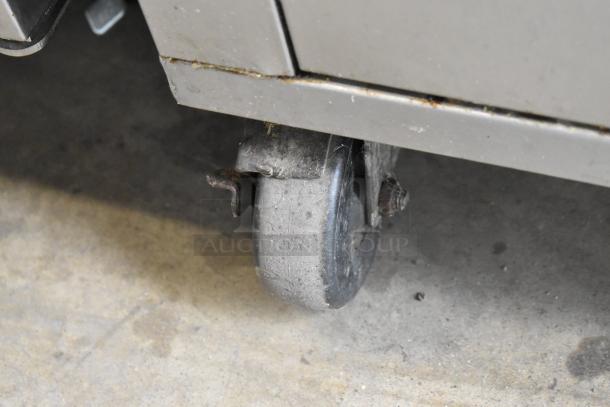 Close-up of a wheel on a Giles stainless steel commercial electric deep fat fryer with ventless grease hood.