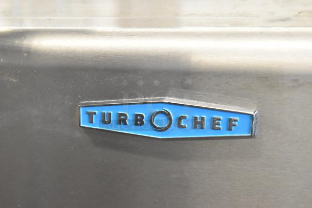 Turbochef logo on stainless steel surface of HhC2020 commercial electric conveyor pizza oven, indicating brand authenticity.
