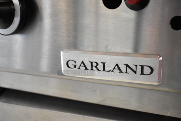 Garland stainless steel commercial gas flat top griddle, close-up of brand logo, features robust construction, used condition.