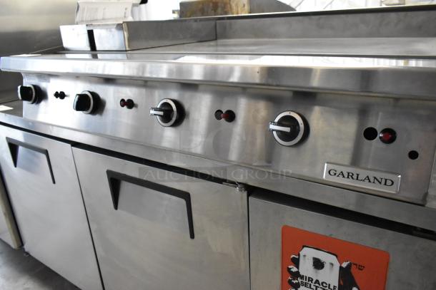 Garland stainless steel commercial gas-powered flat top griddle with control knobs and brand label, in good condition.
