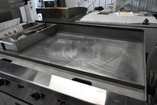 Garland stainless steel commercial gas-powered flat top griddle, gently used, with control knobs, grease tray, and clean surface.