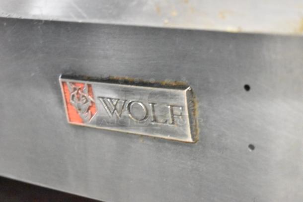 Wolf stainless steel commercial countertop gas griddle on stand, featuring Wolf logo, minor wear visible.