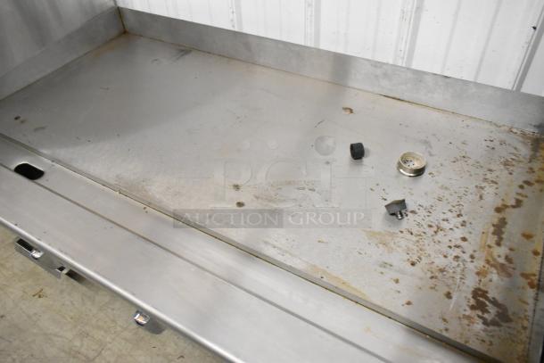 Atosa stainless steel commercial gas griddle with flat top, showing wear and discoloration, buttons detached on surface.