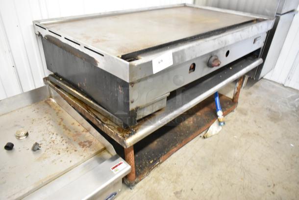 Wolf stainless steel commercial gas griddle on equipment stand, used condition, visible wear, ideal for restaurants.