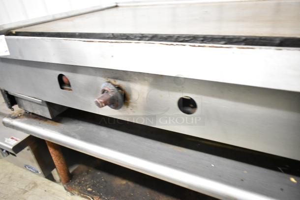 Wolf stainless steel commercial gas griddle on stand, used condition, visible rust on controls, model unspecified.