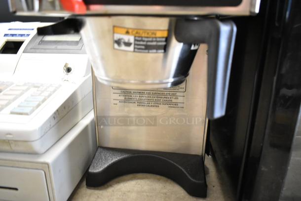 Brand new Grindmaster Grind'n Brew-10H coffee maker, stainless steel, with grinder, hot water dispenser, safety caution visible.