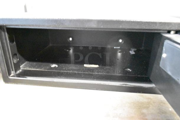 Black metal single compartment safe, open view. No combination included. Interior shows minor wear. Auction item, 2 times your bid.