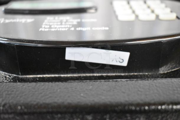 Black metal single compartment safe, no combinations, digital keypad, minor wear, auction label visible.