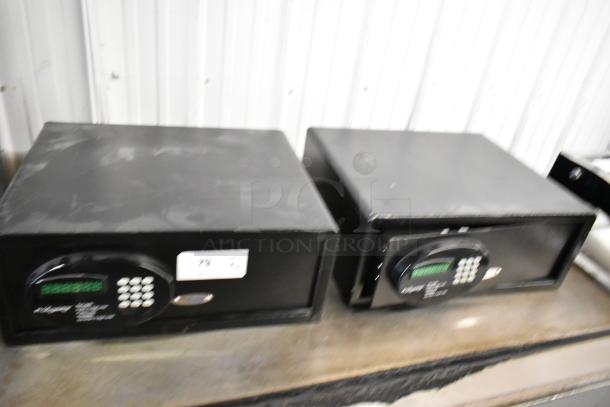 Two black metal single compartment safes, no combinations included, minor scratches, keypad entry, auction label visible.