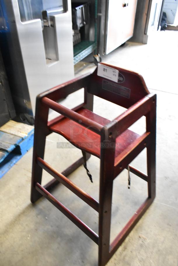 Winco wooden high chair, red finish, sturdy frame, safety strap; slight wear visible; auction tag attached.