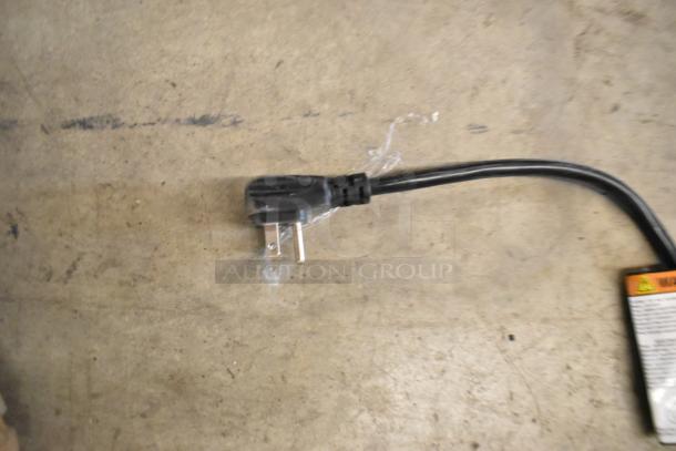 Power cord of a 2019 Habco SE18 commercial cooler. Black three-prong plug on a concrete surface.