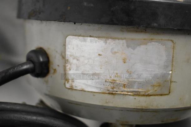 Close-up of Hamilton Beach blender with visible wear and an unclear label. Power cord attached. Suitable for kitchen use.