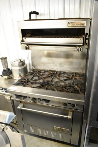 Garland stainless steel 6-burner range with oven, salamander cheese melter, and backsplash. Used condition, visible branding.