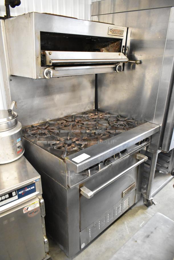 Garland stainless steel commercial 6-burner gas range with oven, salamander cheese melter, and backsplash; used condition.