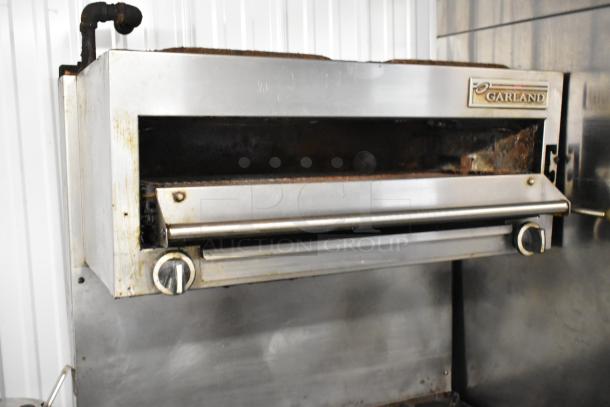Garland stainless steel salamander cheese melter, part of a commercial range. Visible wear, Garland logo on unit.