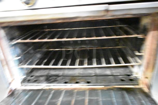 Garland Stainless Steel 6 Burner Range with Oven, natural gas powered, includes salamander cheese melter, and backsplash.