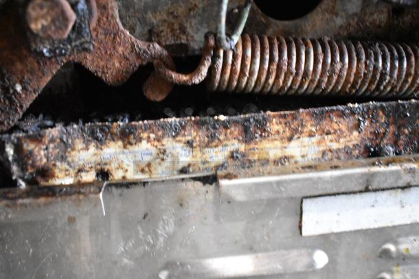 Rust and grime details of Garland stainless steel 6-burner range, indicating wear and use.