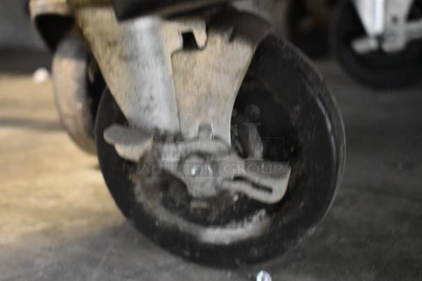 Close-up of a caster wheel from a Duke RUF-48 stainless steel commercial 2-door work top cooler. Visible wear and tear.
