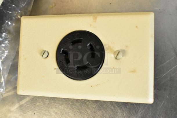 Beige outlet plate with a black 220V NEMA L6-30R socket. Two visible screws. Light wear marks.