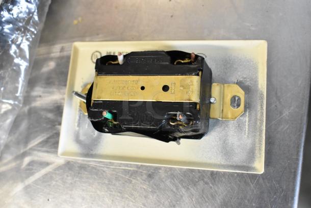 Electrical outlet with black and brass components, labeled "14". Mounted on metal, wires attached. Good condition, ready for use.