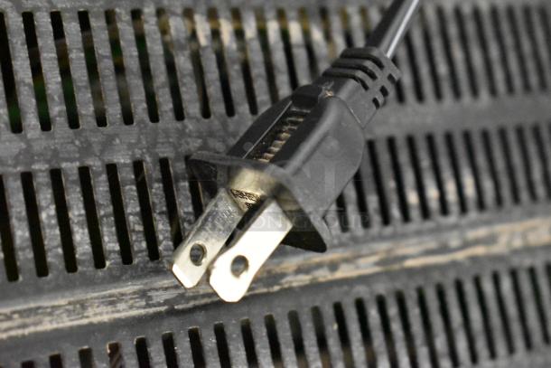 Close-up of a power plug on a slotted surface, likely belonging to the Onkyo AV Receiver included with a dining height table.