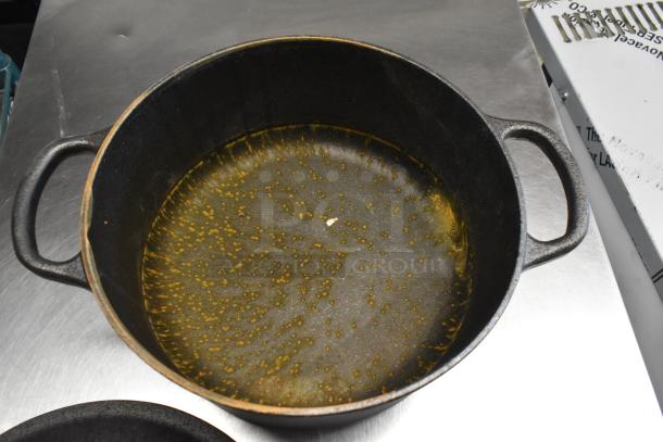 Antique cast iron pot with handles, visible wear, and seasoning on interior. Lid included, suitable for cooking and collectibility.