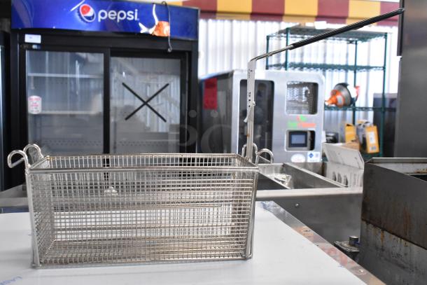 "Brand new metal fry basket with minor scratches, rectangular, mesh design, and a sturdy handle for commercial use."