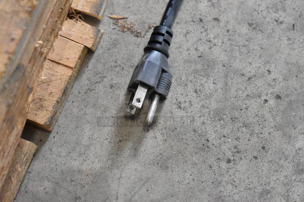 Power plug on concrete floor next to wooden pallet, part of Vollrath 3646610 hot food well.