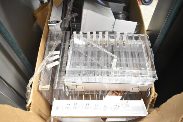 Box of assorted items including transparent shelves, plastic components, and metal brackets, in good condition.