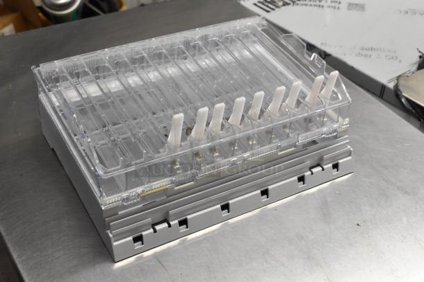 Clear plastic holder with dividers and white pegs, stacked on gray base, in good condition.