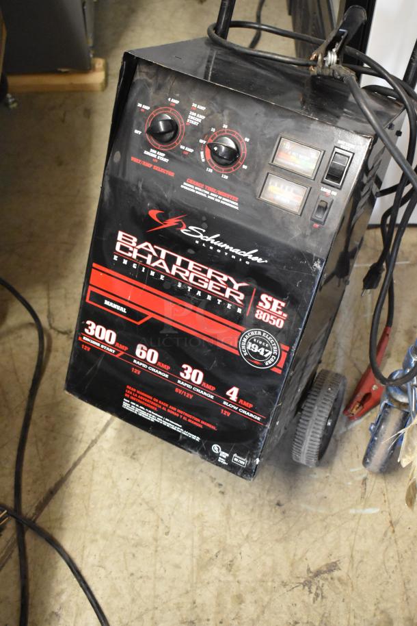 Schumacher SE 8050 Battery Charger, engine starter, 300-amp, black, wheeled, dual dials, voltage display, well-used condition.