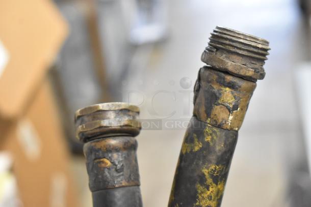 Two weathered hoses with metal fittings, showing signs of wear and patina, suitable for industrial use or repair.