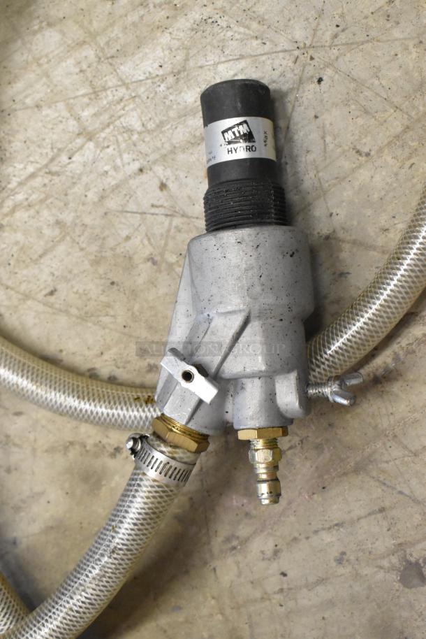 Dual hoses with NTM Hydro label, metal fittings, and clamps, showing some wear on concrete floor.