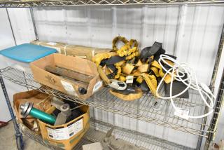 Tiered shelf with assorted items including straps, metal pieces, a stand, and a blue-lid container. Mixed condition.