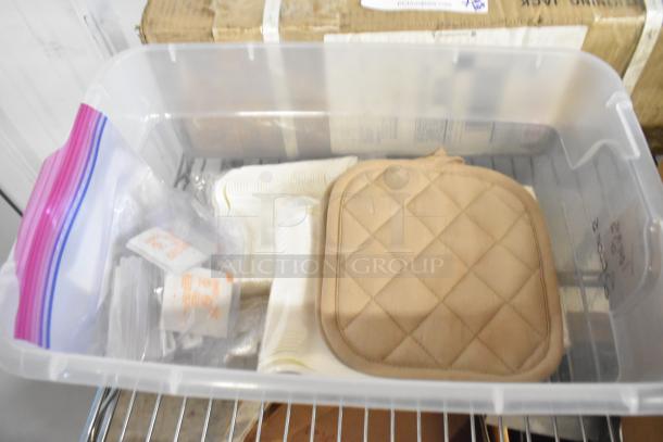 Clear plastic bin with a quilted cushion, zipper bags, metal pieces, and fabric. Suitable for crafting or repairs.