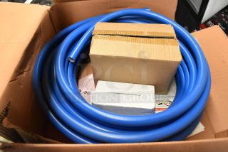 Cardboard box containing coiled blue plastic tubing and smaller boxes, possibly indicating included parts, in good condition.