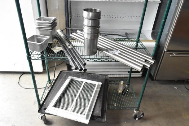 Auction lot includes stainless steel drop-in bins, metal rods, and assorted materials on a two-tier green cart.