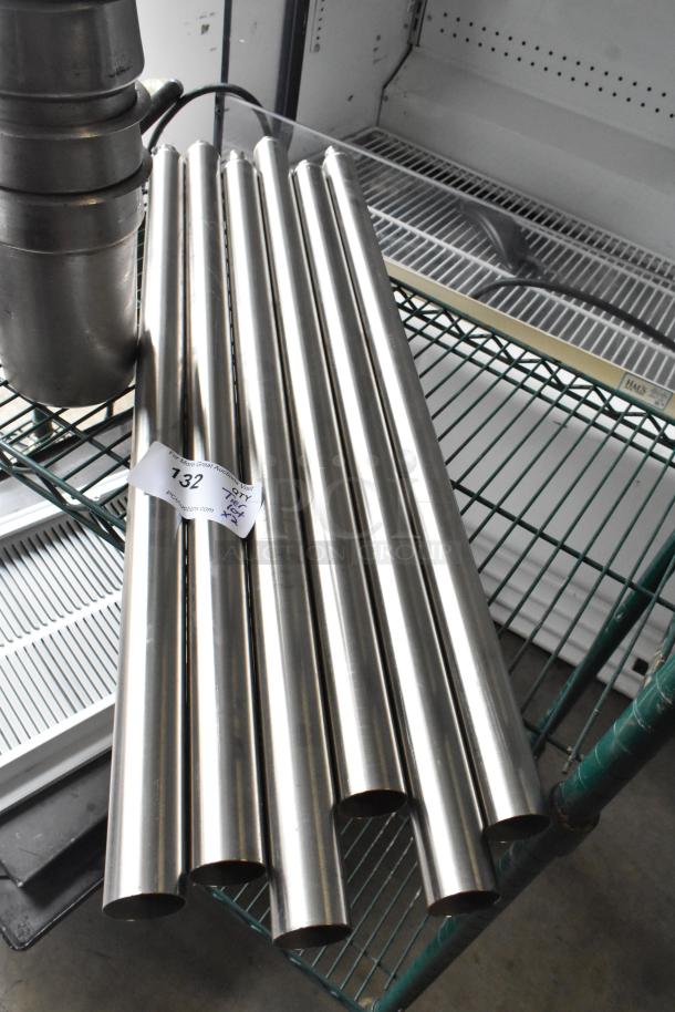 Lot of stainless steel items including drop-in bins and metal rods, shown on a rack. Auction tag labeled "132".