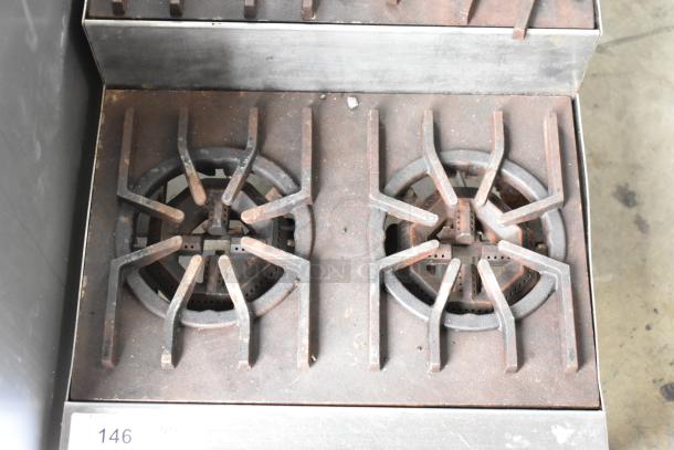 Metal commercial countertop gas-powered 4-burner 2-tier range, used condition, with visible rust and wear on burners.
